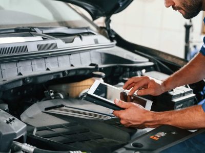 Using tablet. Auto mechanic working in garage. Repair service.